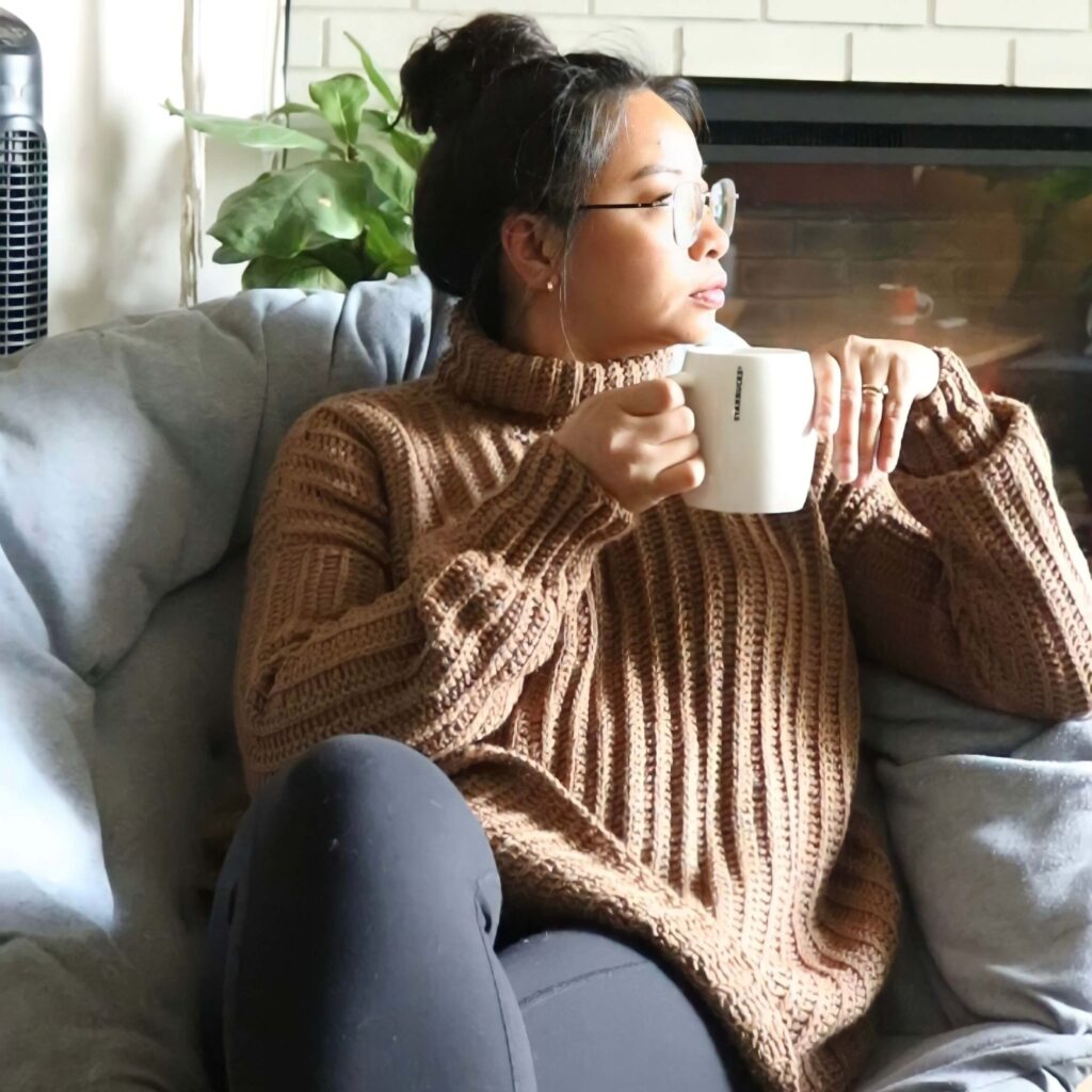 girl sipping coffee wearing a comfy crochet sweater